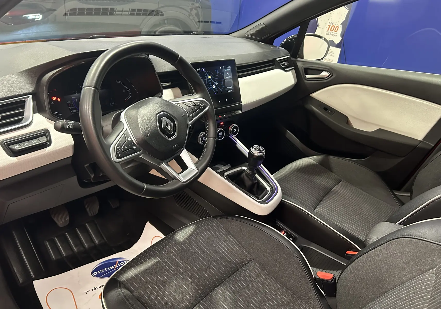 Vue intérieure côté conducteur de la Renault Clio V TCe 90 TECHNO rouge, avec volant multifonction et boîte manuelle.