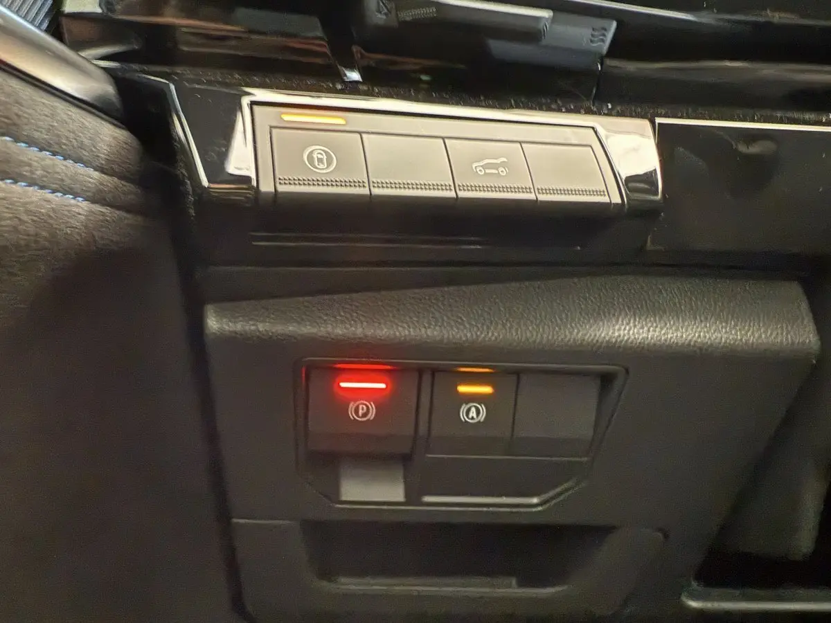Gros plan sur les commandes de verrouillage et assistance au freinage du tableau de bord du Renault Espace gris foncé esprit Alpine 2025.