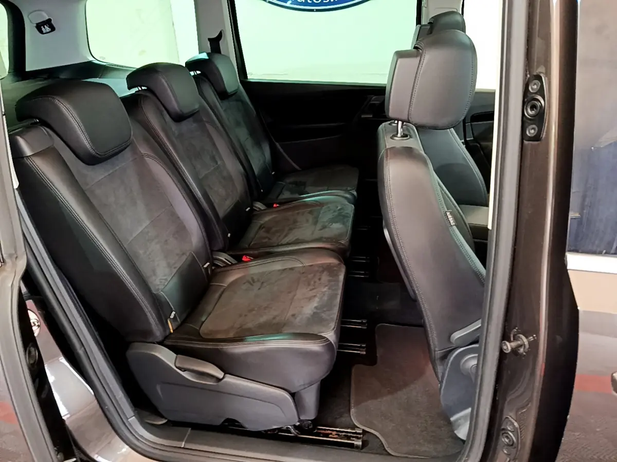 Vue latérale intérieure montrant la deuxième rangée de sièges en cuir noir du Volkswagen Sharan marron de 2017.