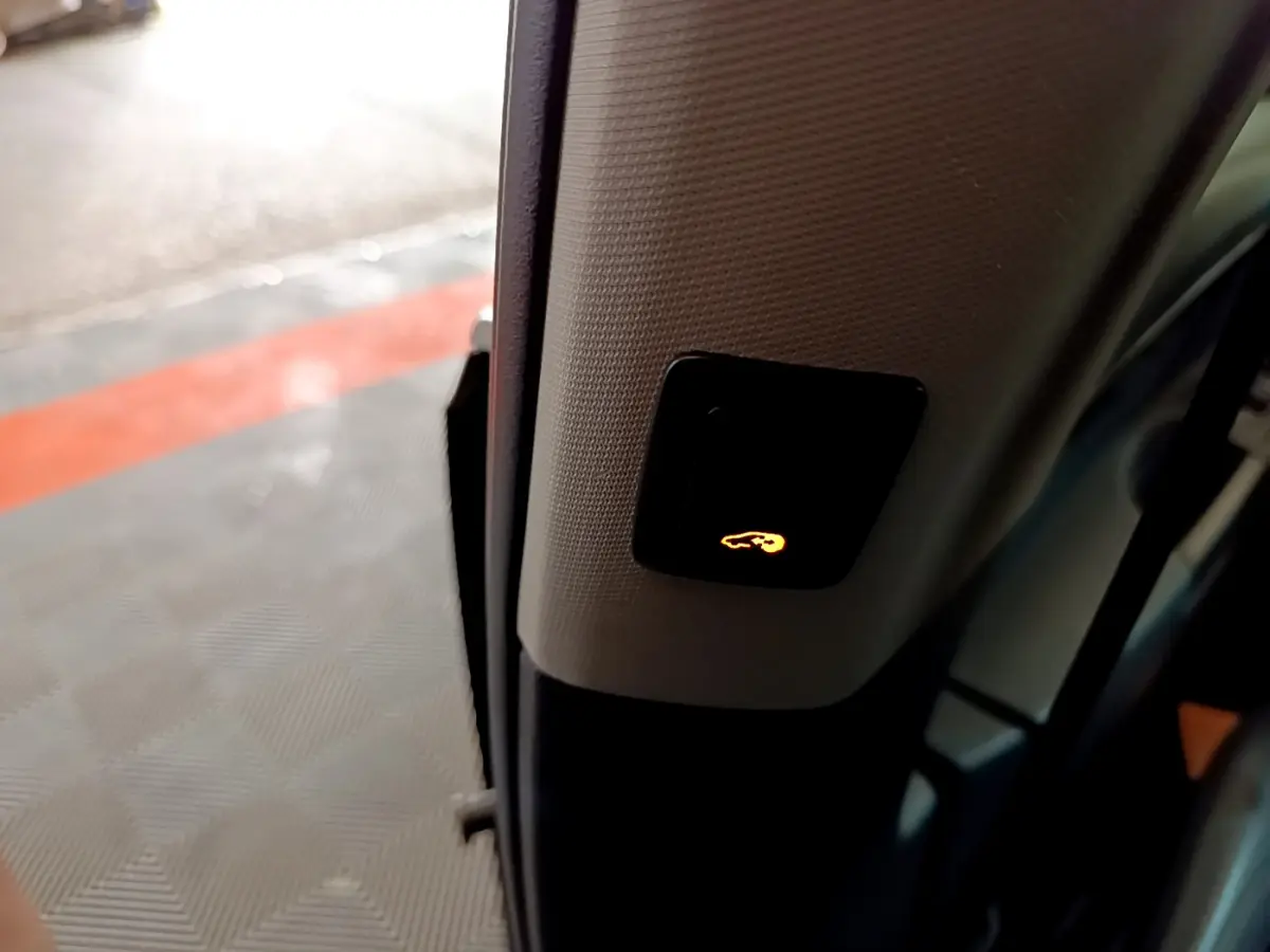 Bouton lumineux de fermeture électrique du hayon sur le montant intérieur d'une Volkswagen Sharan marron, vue rapprochée côté porte ouverte.
