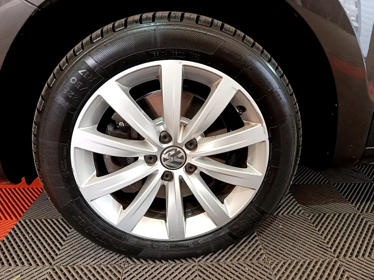 Gros plan sur la roue avant droite argentée du Volkswagen Sharan marron, mettant en valeur la jante à 10 branches.