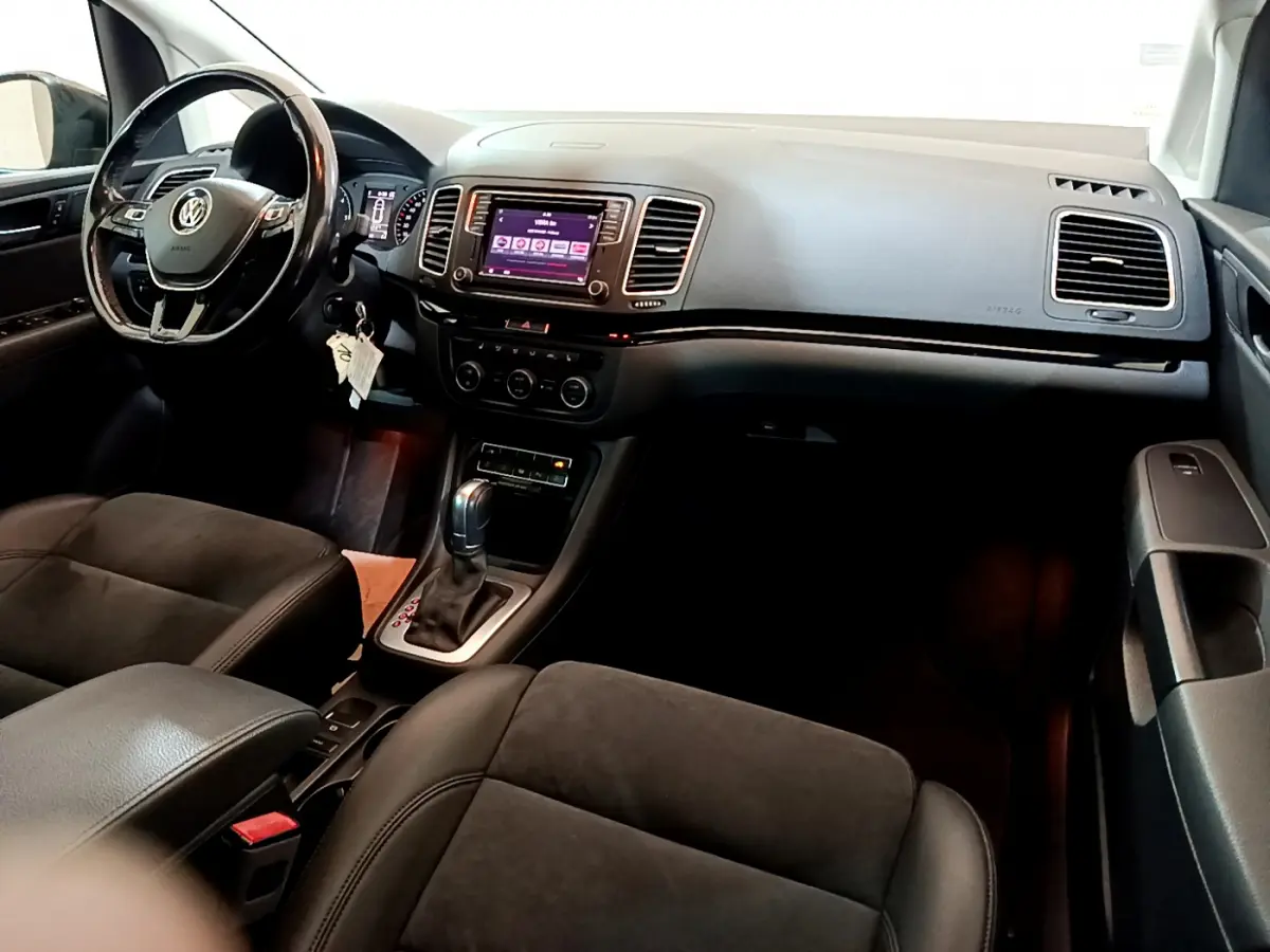 Vue intérieure avant droite du Volkswagen Sharan 2017 avec tableau de bord noir et écran tactile central.