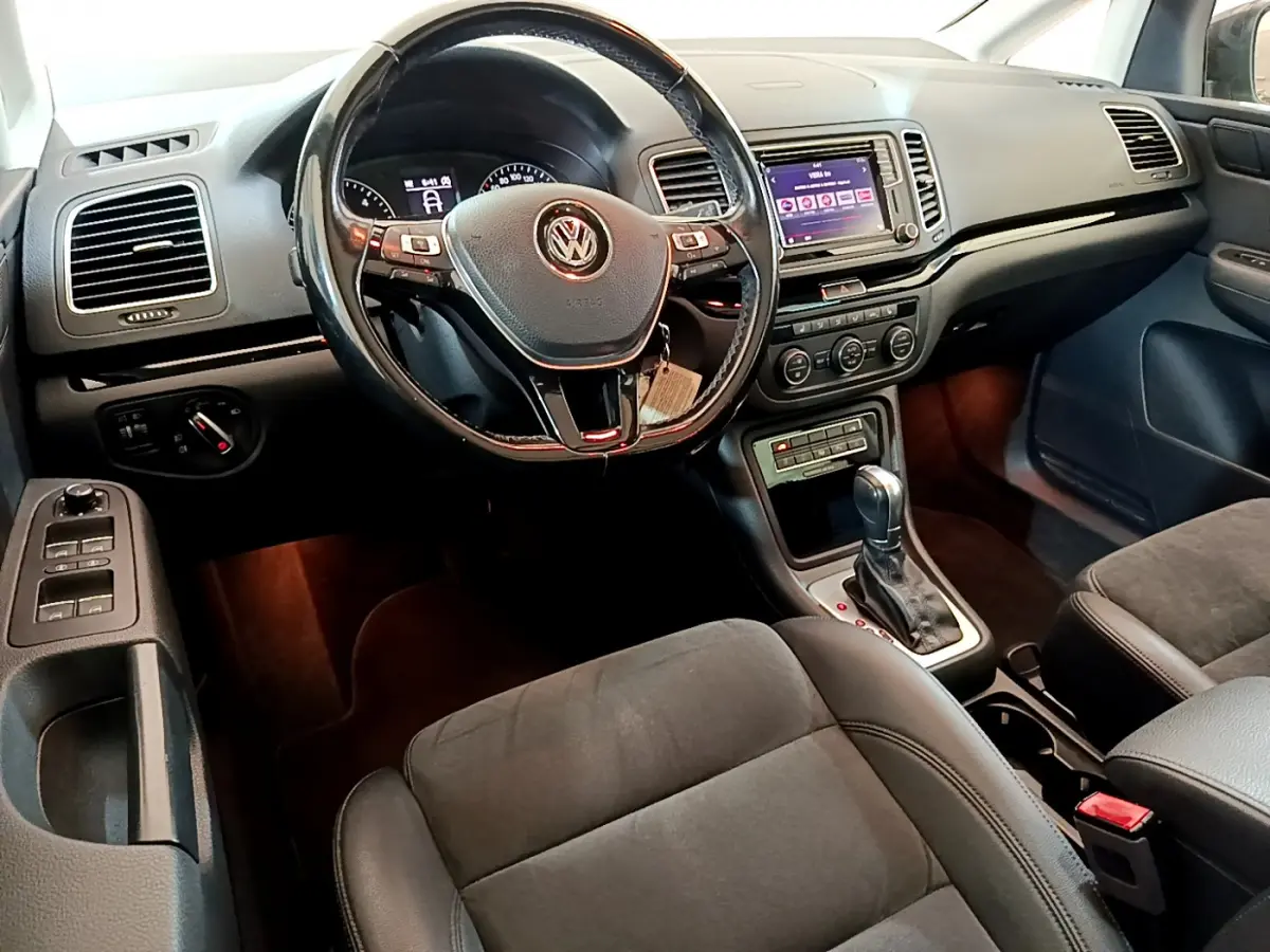 Intérieur du Volkswagen Sharan 2017, vue du poste de conduite avec volant cuir et écran tactile central.