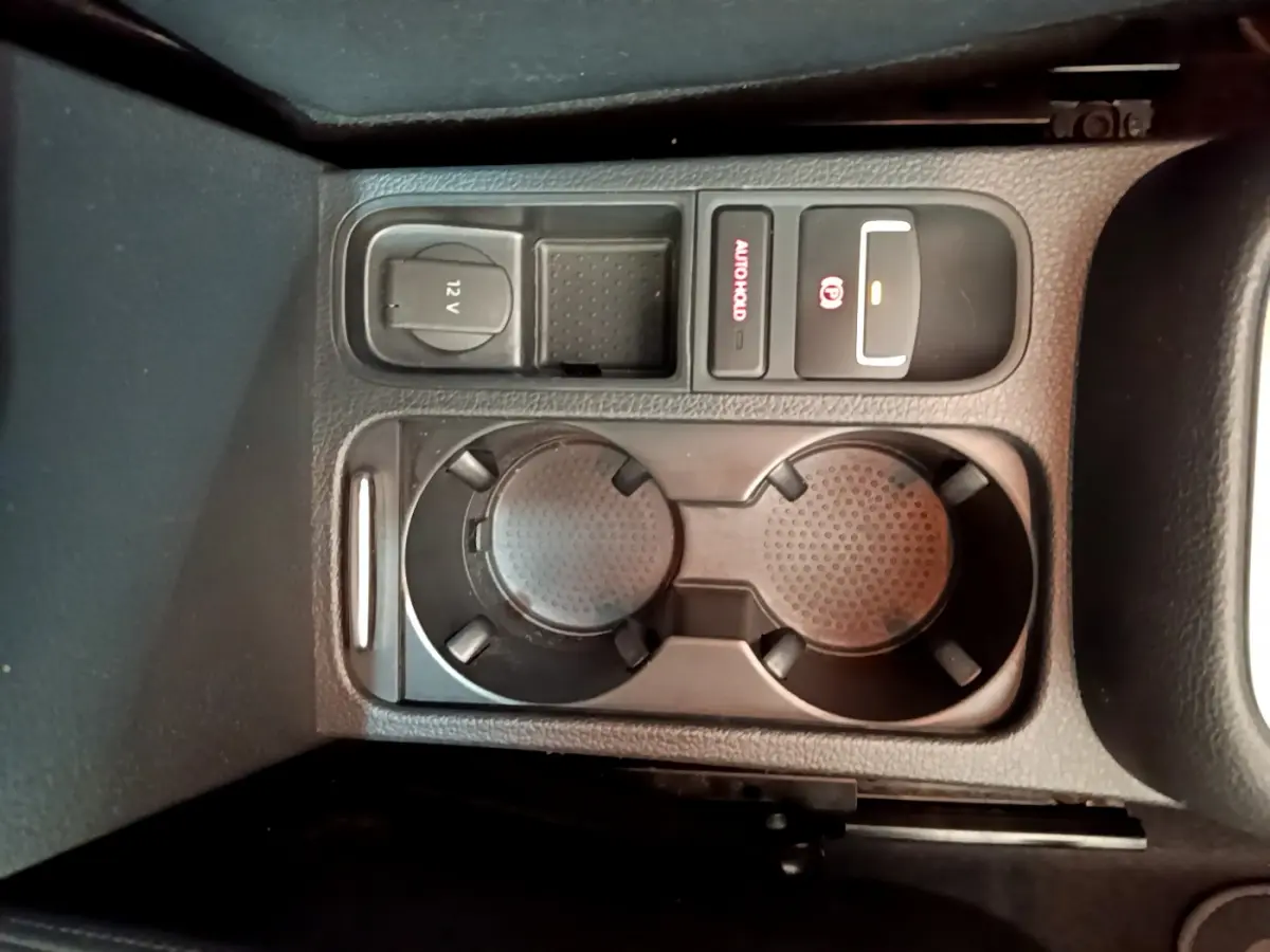 Vue en plongée sur la console centrale noire du Volkswagen Sharan 2017 montrant porte-gobelets et commandes électriques.