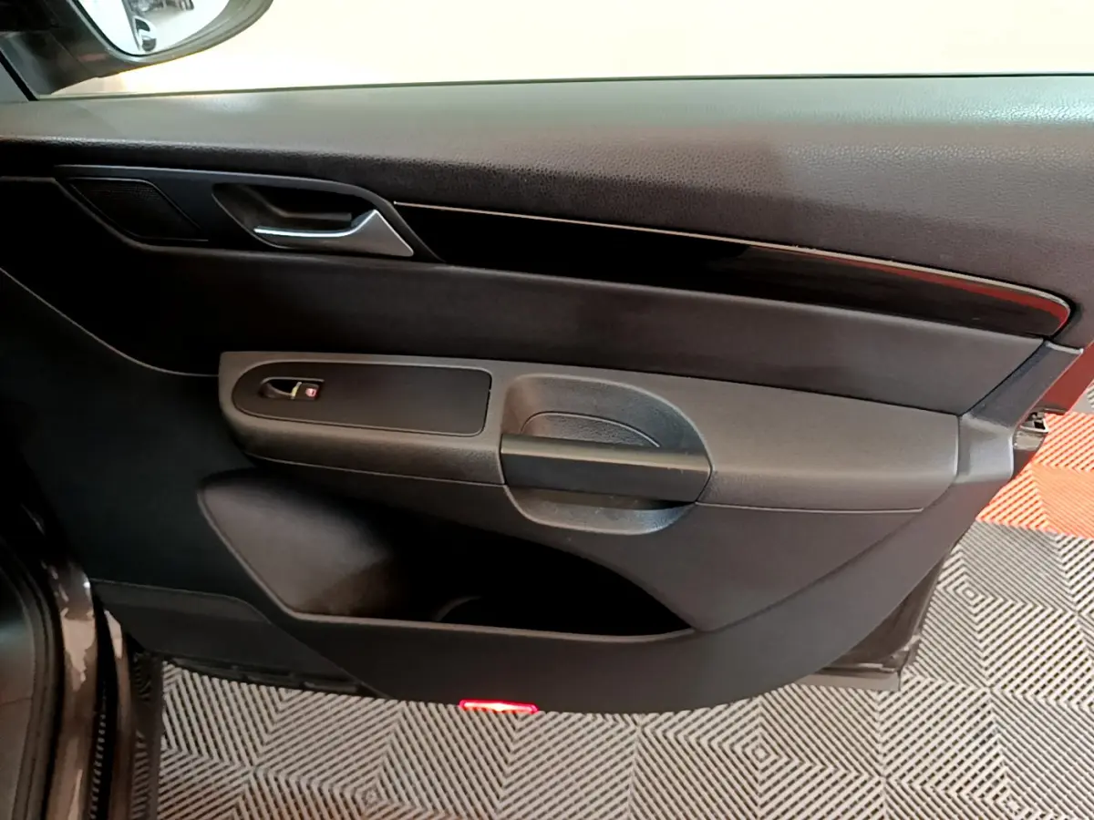 Vue rapprochée de la porte côté gauche noire du Volkswagen Sharan 2017 avec poignée et insert bois foncé.