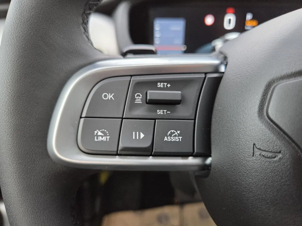 Gros plan sur les commandes au volant noir du Jeep Avenger 2025, avec boutons de régulateur et assistance de conduite.