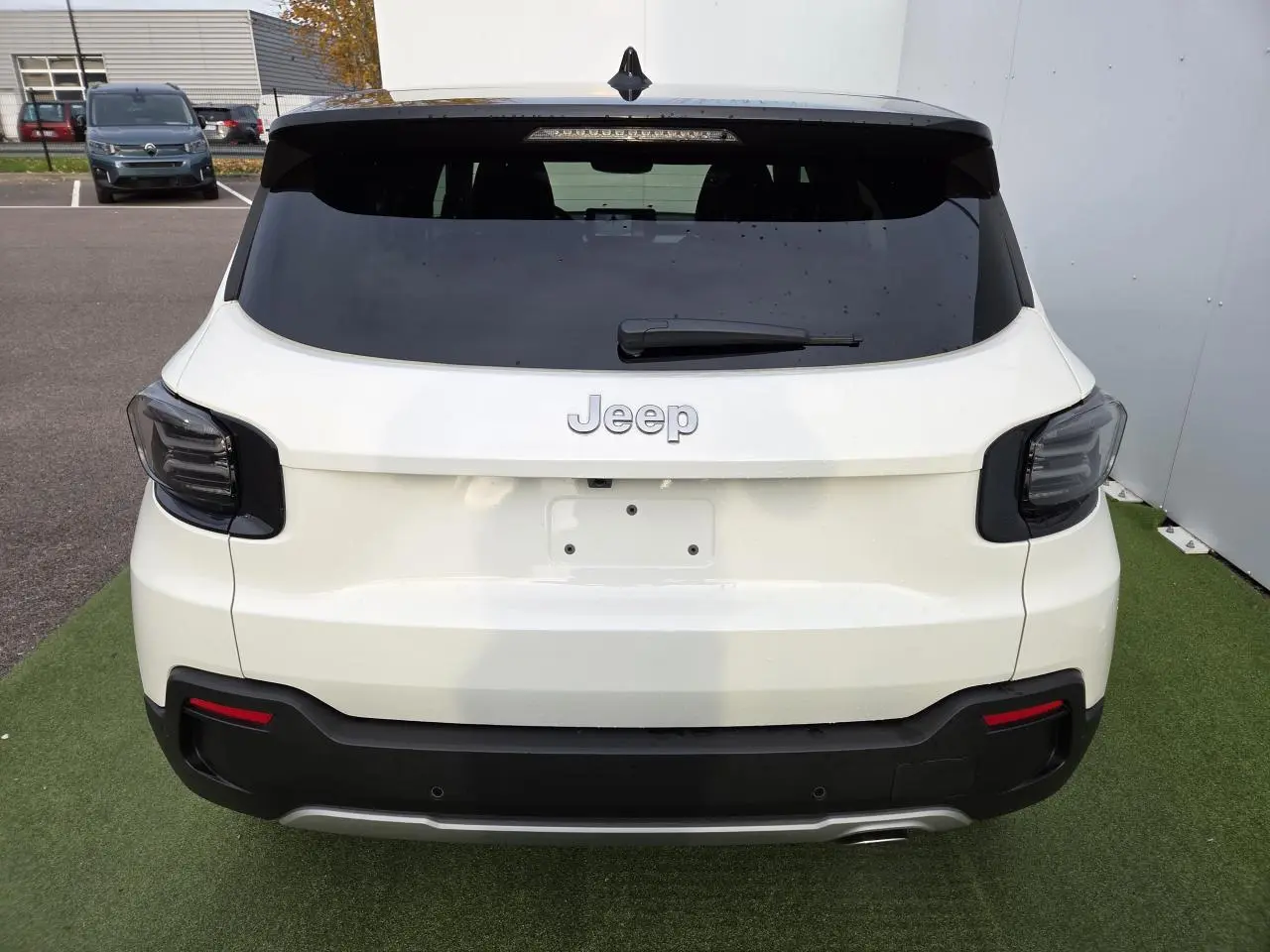 Vue arrière d'un Jeep Avenger 2025 blanc Snow avec toit noir Volcano et feux arrière LED fumés.