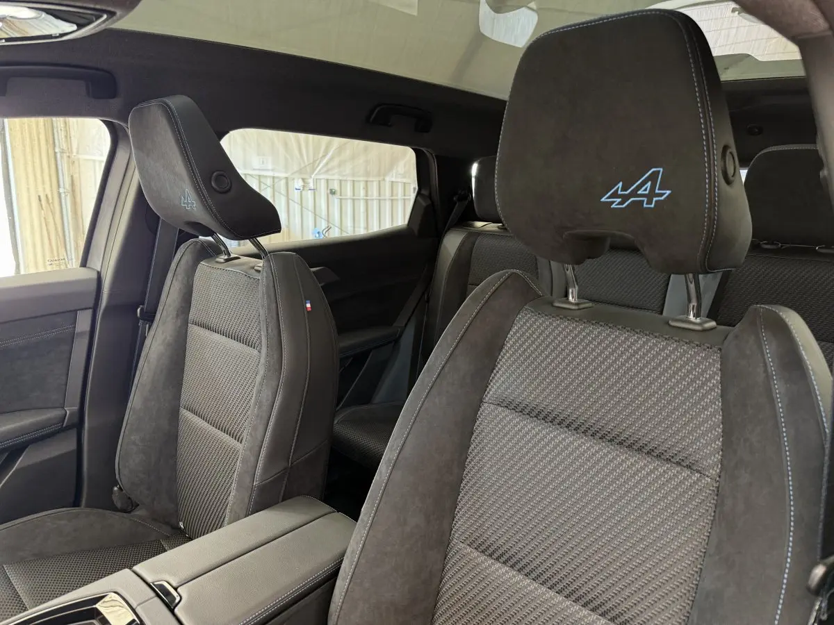 Vue intérieure côté droit des sièges avant en suède gris foncé avec logo Alpine bleu sur appuie-tête du Renault Espace 2025 esprit Alpine.
