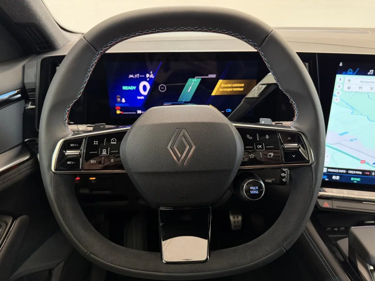Vue rapprochée du volant en cuir et suède noir du Renault Espace esprit Alpine 2025 avec tableau de bord numérique et écran tactile.