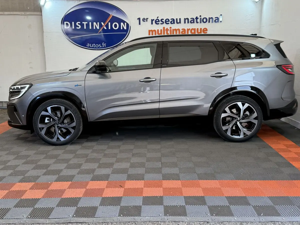 Profil côté gauche d'un Renault Espace gris foncé esprit Alpine 7 places, roues alliage et toit noir visible en intérieur showroom.