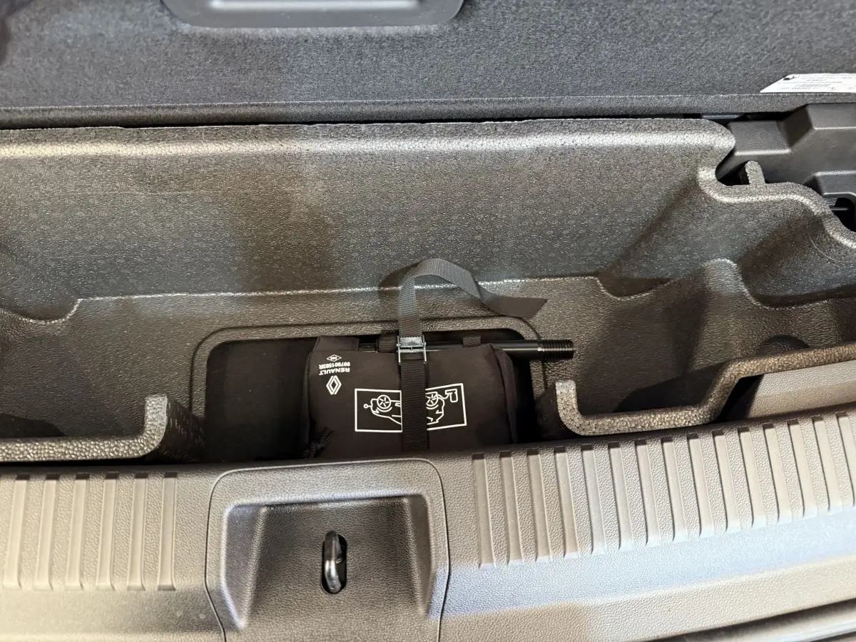 Compartiment de rangement sous le plancher du coffre du Renault Espace gris foncé, avec kit de réparation pneus visible.