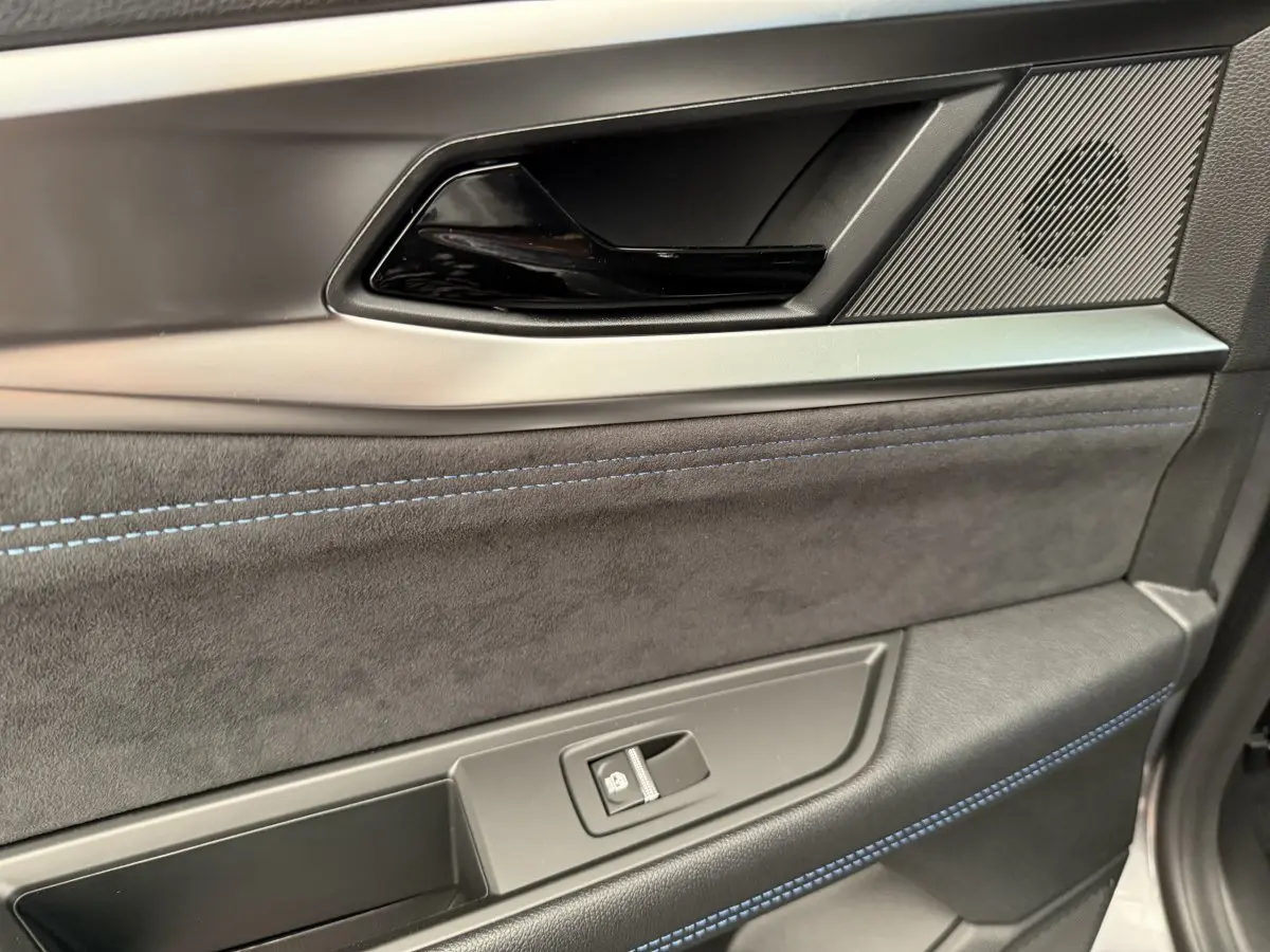 Gros plan sur la garniture intérieure de porte avant droite du Renault Espace gris foncé esprit Alpine 2025, avec surpiqûres bleues.