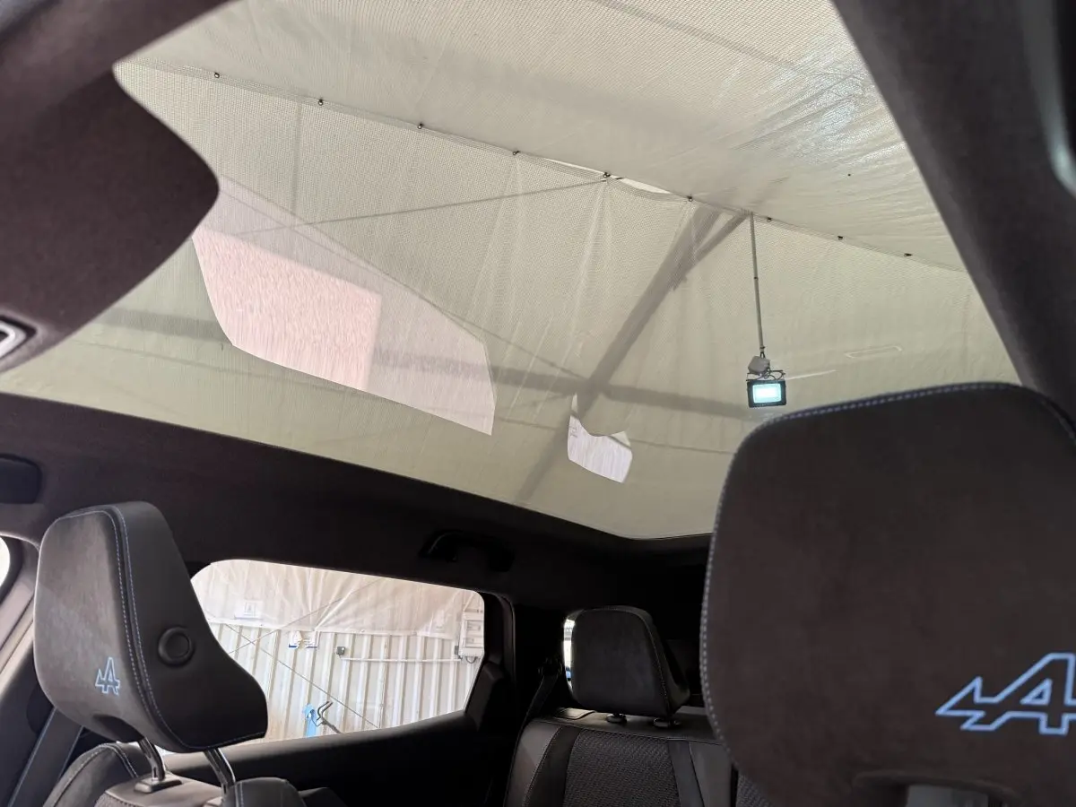 Vue intérieure arrière montrant les appuis-tête noirs avec logo Alpine bleu et toit panoramique du Renault Espace gris foncé esprit Alpine.