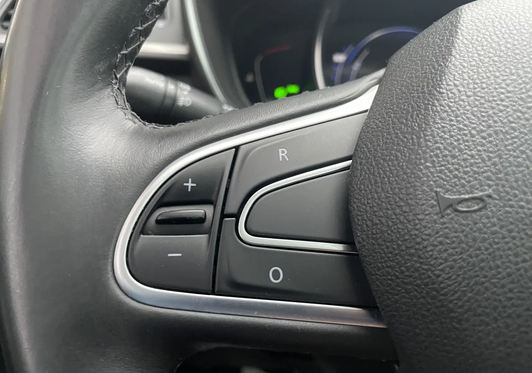 Gros plan sur les commandes de régulateur de vitesse au volant en cuir noir du Renault Kadjar gris titanium 2018.