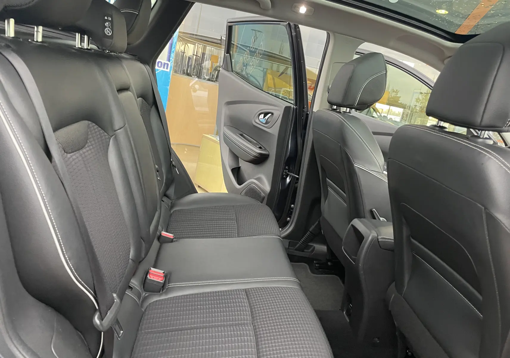 Intérieur arrière du Renault Kadjar gris titanium 2018, sièges tissu gris noir avec porte arrière droite ouverte.