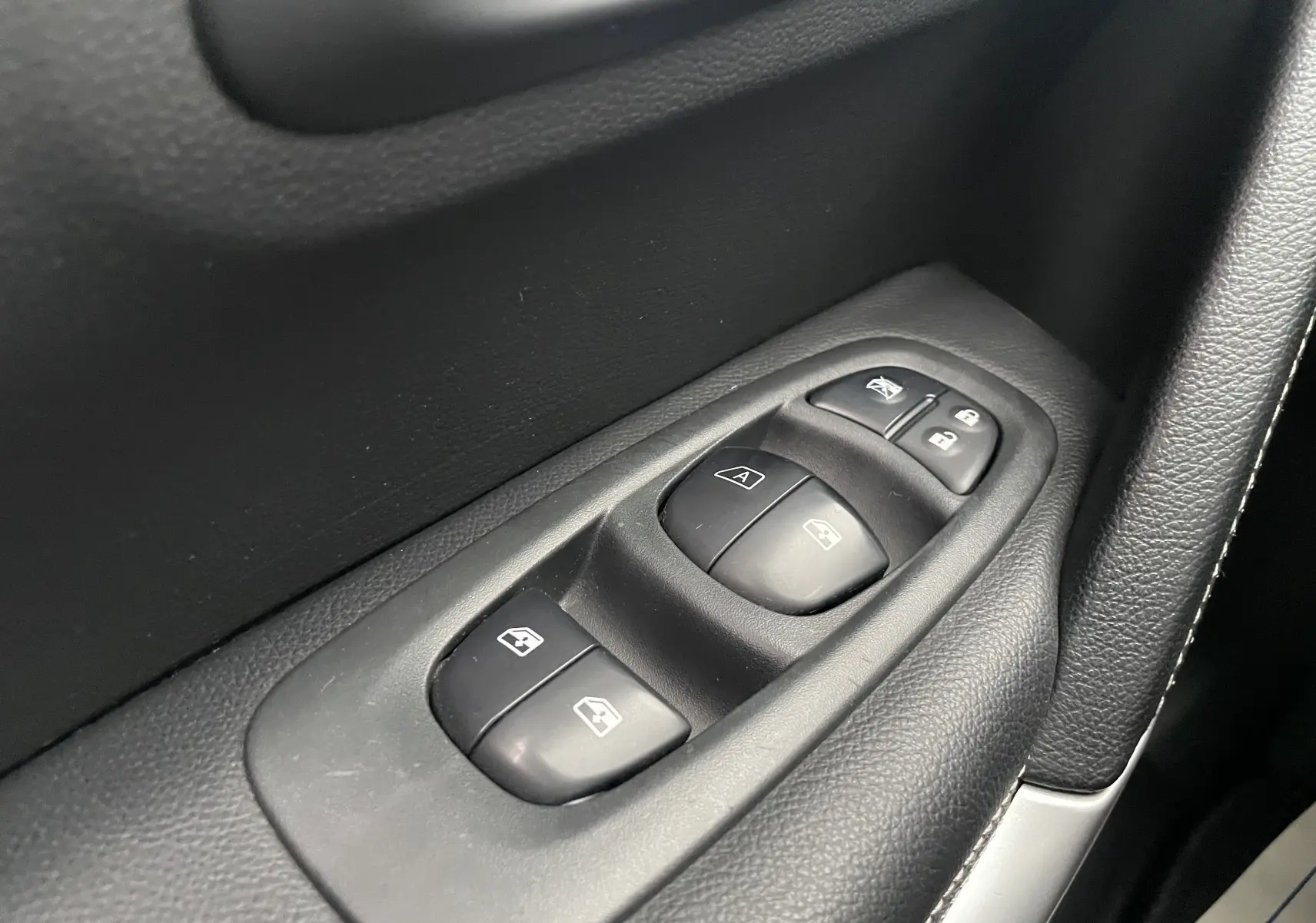 Gros plan sur les commandes des vitres électriques côté conducteur du Renault Kadjar 1.5 DCI 110 EDC Bose avec garniture noire.