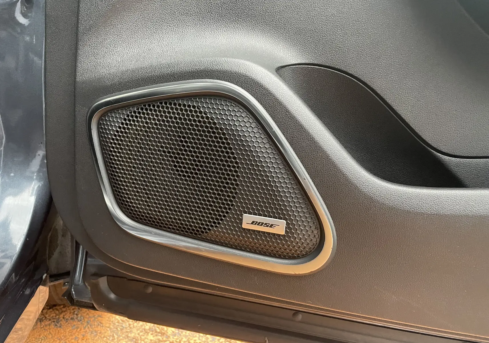 Gros plan sur l'enceinte Bose intégrée à la porte intérieure d'un Renault Kadjar gris titanium de 2018.