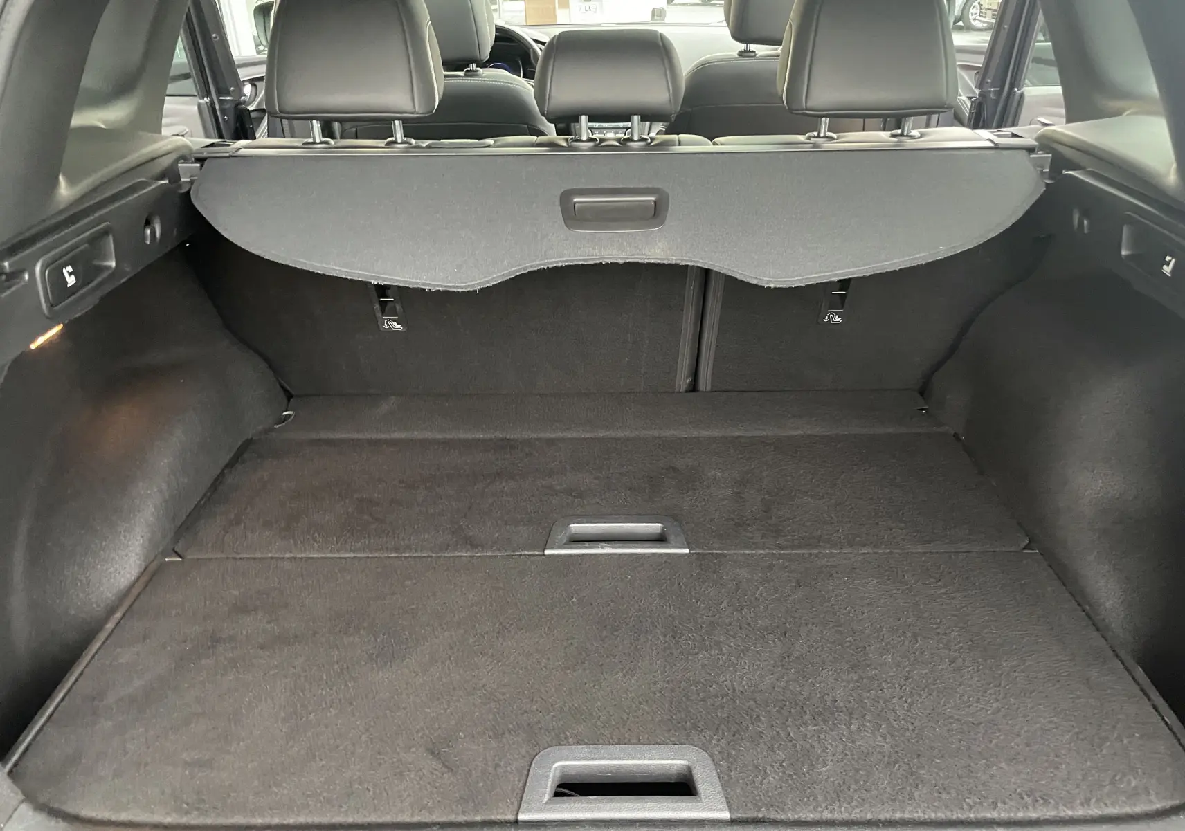 Vue intérieure du coffre spacieux du Renault Kadjar gris titanium, avec cache-bagages et sièges arrière en tissu gris-noir visibles.