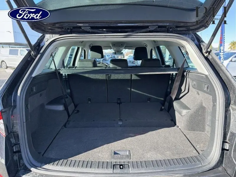 Coffre ouvert vu de l'arrière d'un Skoda Kodiaq noir Magic Nacré 2023 avec banquette arrière et cache-bagages.