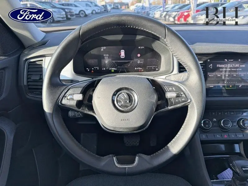 Vue intérieure centrée sur le volant cuir multifonction noir du Skoda Kodiaq avec tableau de bord numérique et écran tactile.