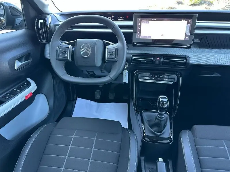 Vue intérieure avant de la Citroën C3 1.2 Turbo 2025, volant multifonction, tableau de bord noir et écran tactile central.