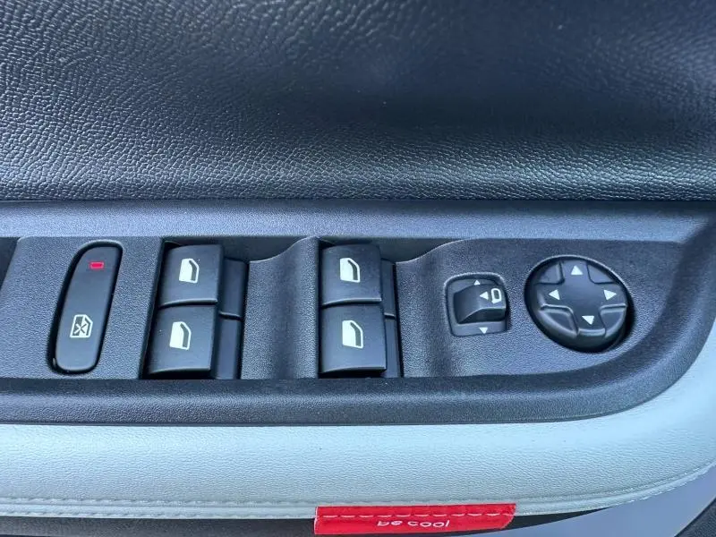 Gros plan sur les commandes de lève-vitres et réglage des rétroviseurs côté conducteur de la Citroën C3 2025 Noir Perla Nera.