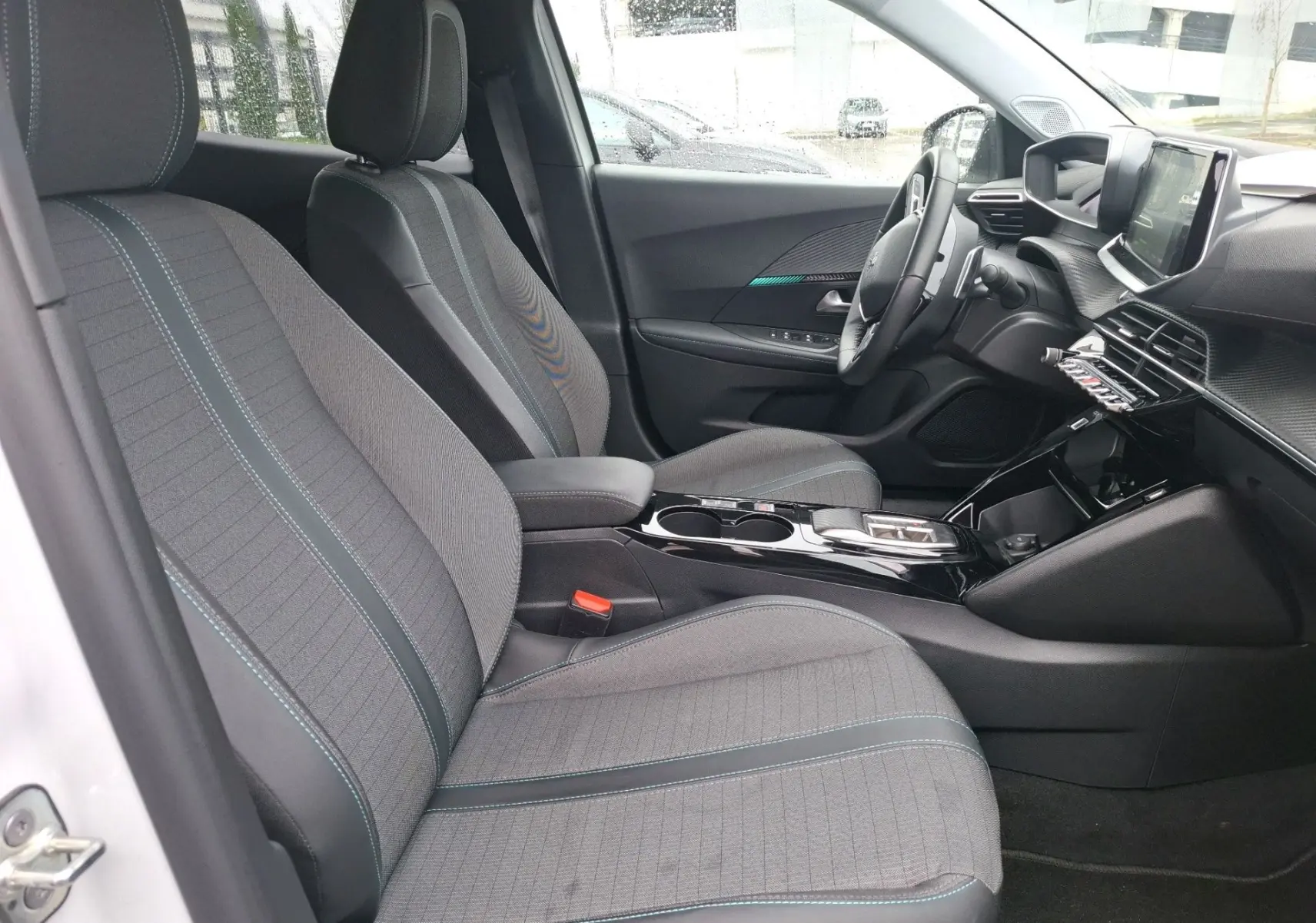 Intérieur avant droit du Peugeot 2008 blanc nacré 2022, sièges tissu gris avec surpiqûres bleues et tableau de bord moderne.