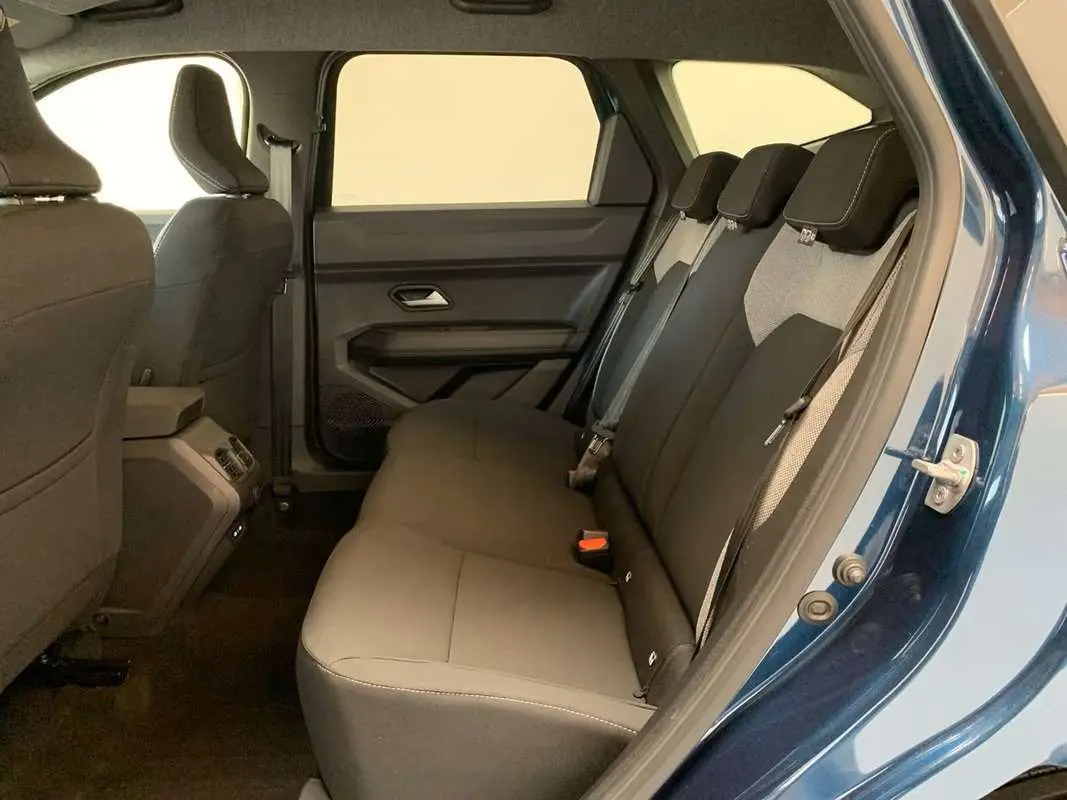 Vue intérieure côté droit sur la banquette arrière grise du Dacia Bigster bleu indigo avec portes ouvertes.