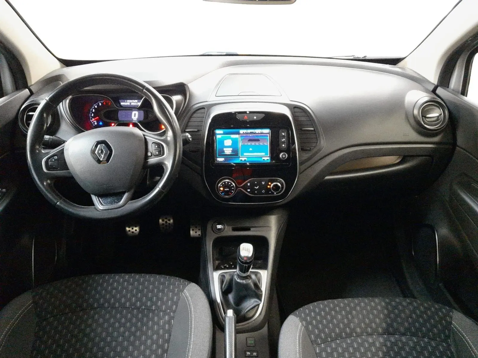 Vue intérieure frontale du tableau de bord du Renault Captur TCE 120 Energy Iridium 2017 avec volant, écran tactile et boîte manuelle.
