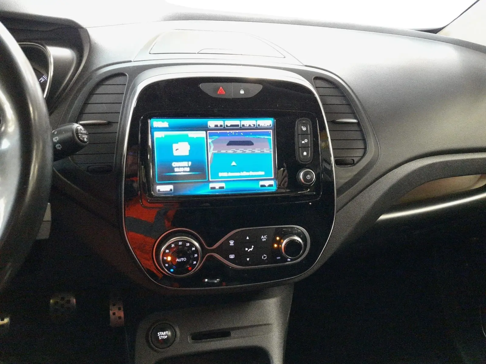 Vue intérieure centrée sur la console centrale du Renault Captur TCe 120 Energy Iridium avec écran tactile et commandes de climatisation.