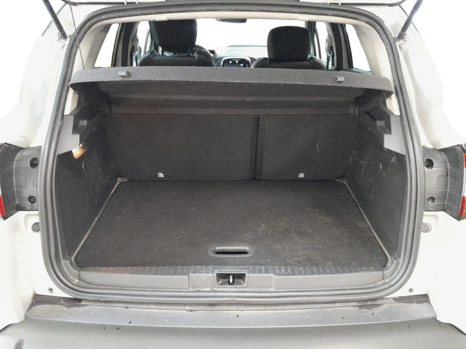 Coffre ouvert vu de l'arrière d'un Renault Captur gris clair métal avec intérieur noir et banquette arrière visible.