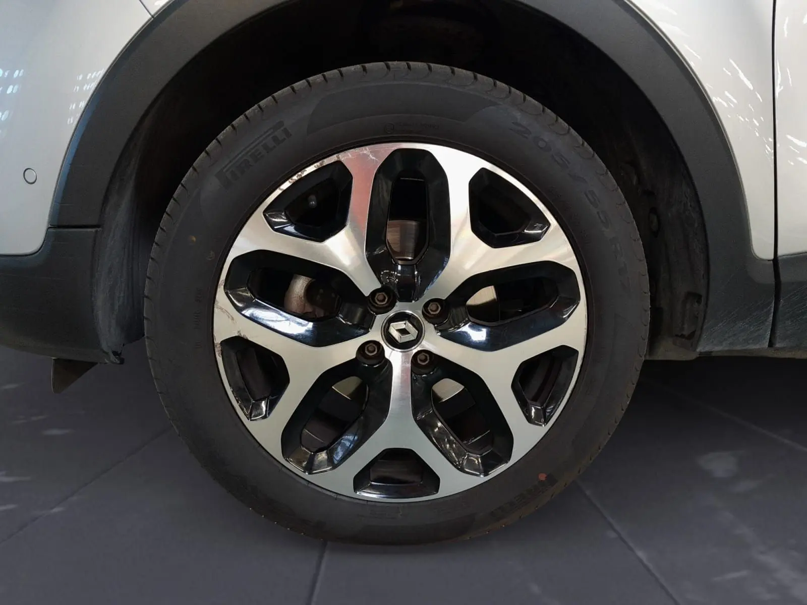 Gros plan sur la jante alliage 17 pouces bicolore noir et argent du Renault Captur gris clair métal de 2017.