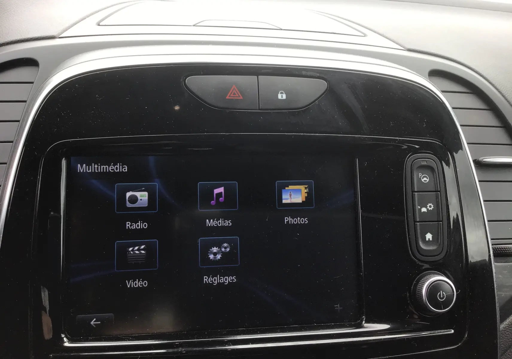 Écran tactile multimédia du tableau de bord d'une Renault Captur 2017, avec commandes et finition noire brillante.