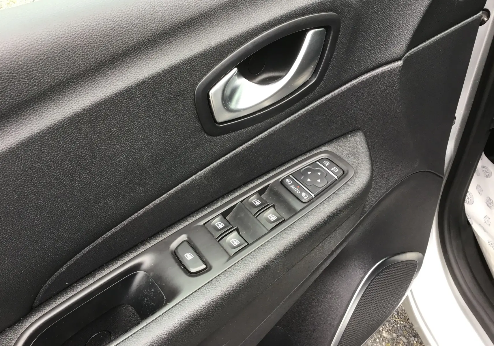 Gros plan sur la porte avant gauche noire du Renault Captur 2017, montrant les commandes électriques des vitres et la poignée argentée.