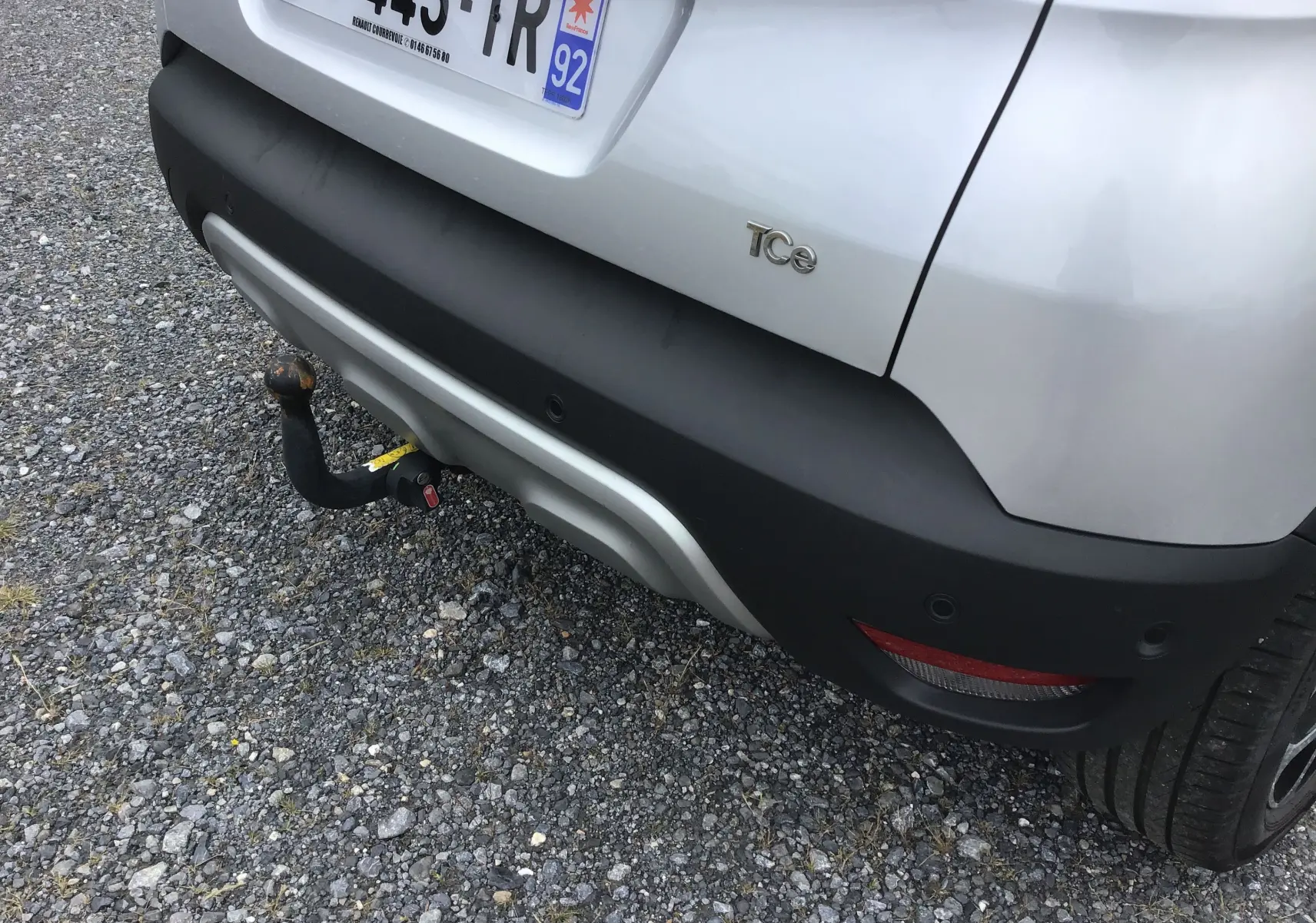 Vue arrière droite du Renault Captur gris clair métal avec attelage visible et détails noirs sur le pare-chocs.