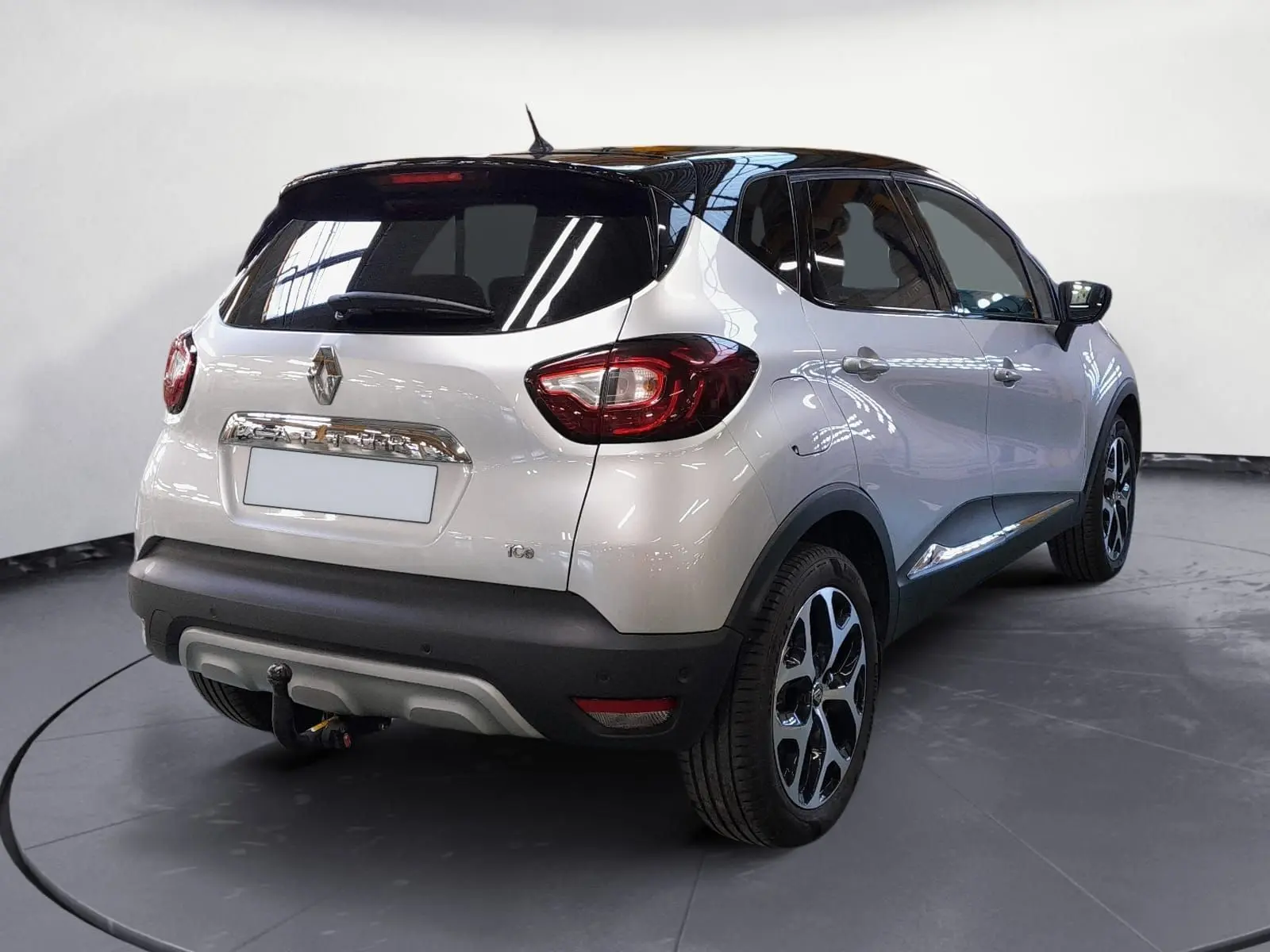 Vue 3/4 arrière droite d'un Renault Captur TCE 120 Energy Iridium gris clair métallisé avec toit noir et jantes alliage 17 pouces.