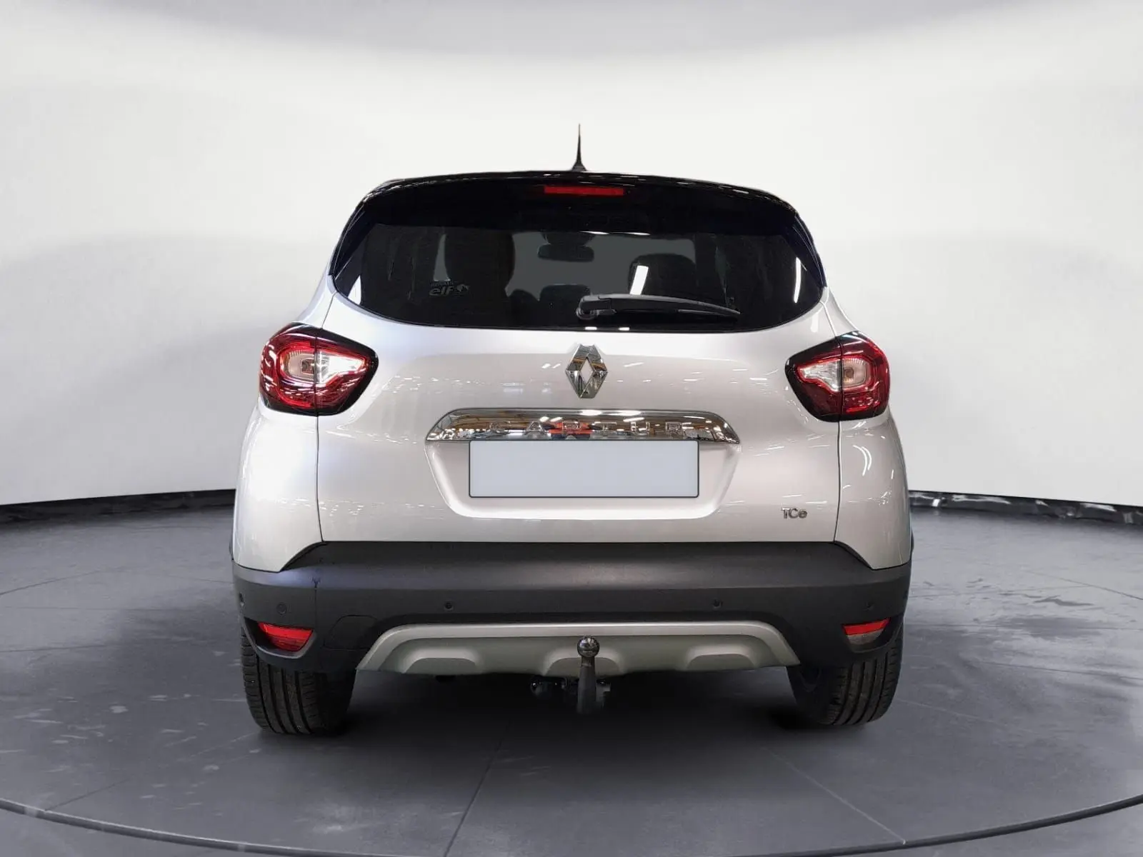 Vue arrière d'un Renault Captur gris clair métal avec toit noir, équipé d'une attache-remorque visible.