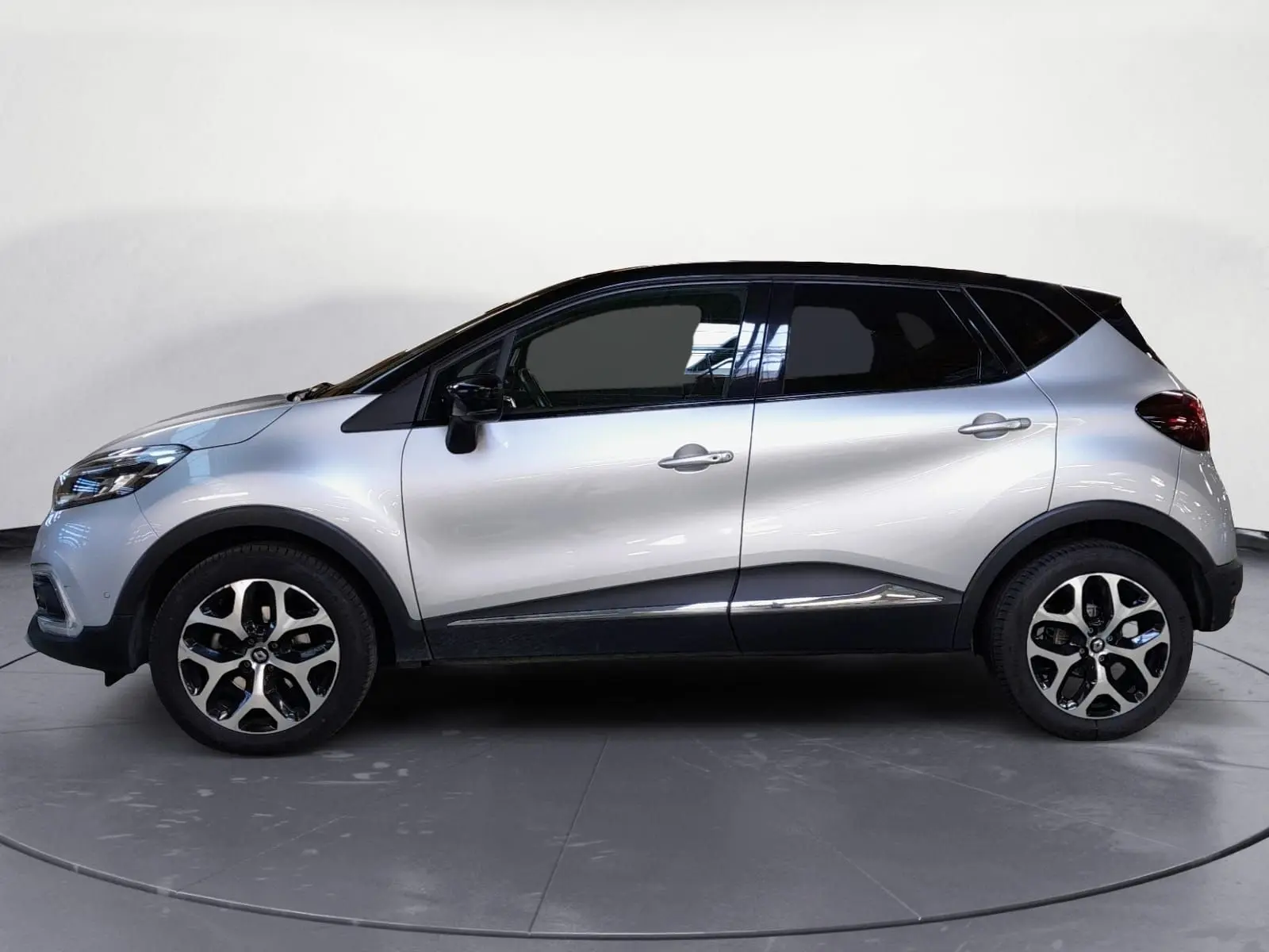 Profil droit du Renault Captur TCE 120 Energy Iridium 2017 en gris clair métal avec toit noir et jantes alliage 17 pouces.