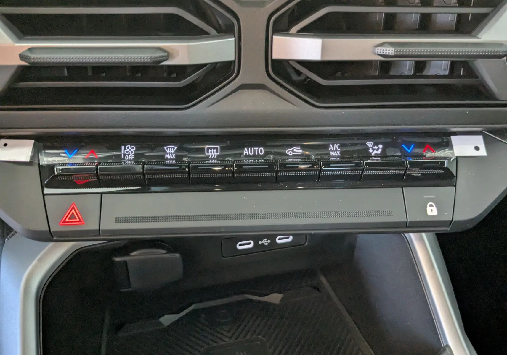 Vue rapprochée de la console centrale du Dacia Bigster Hybrid 155 Journey 2026, montrant les commandes de climatisation et les ports USB.