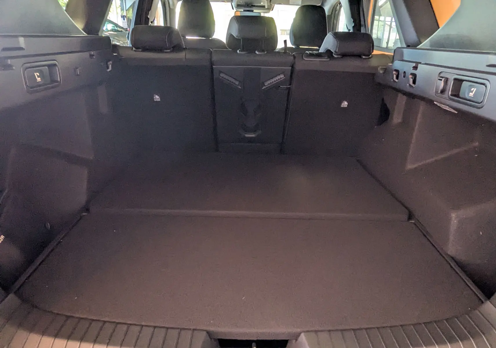 Coffre spacieux du Dacia Bigster Hybrid 155 Journey vu de l'arrière, intérieur noir avec banquette arrière rabattue.