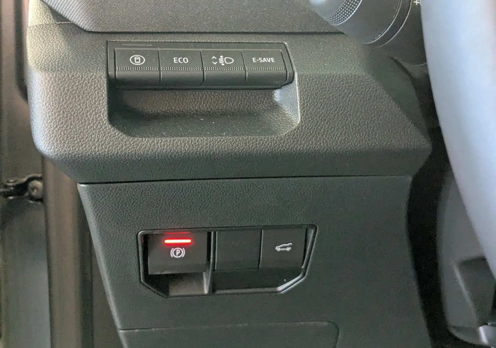Gros plan sur les commandes du tableau de bord du Dacia Bigster Hybrid 155 Journey, boutons de fonctions et frein à main électronique.