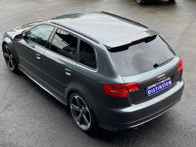 Audi RS3 Sportback gris Daytona vue 3/4 arrière droite, avec jantes alliage foncé et vitres teintées.