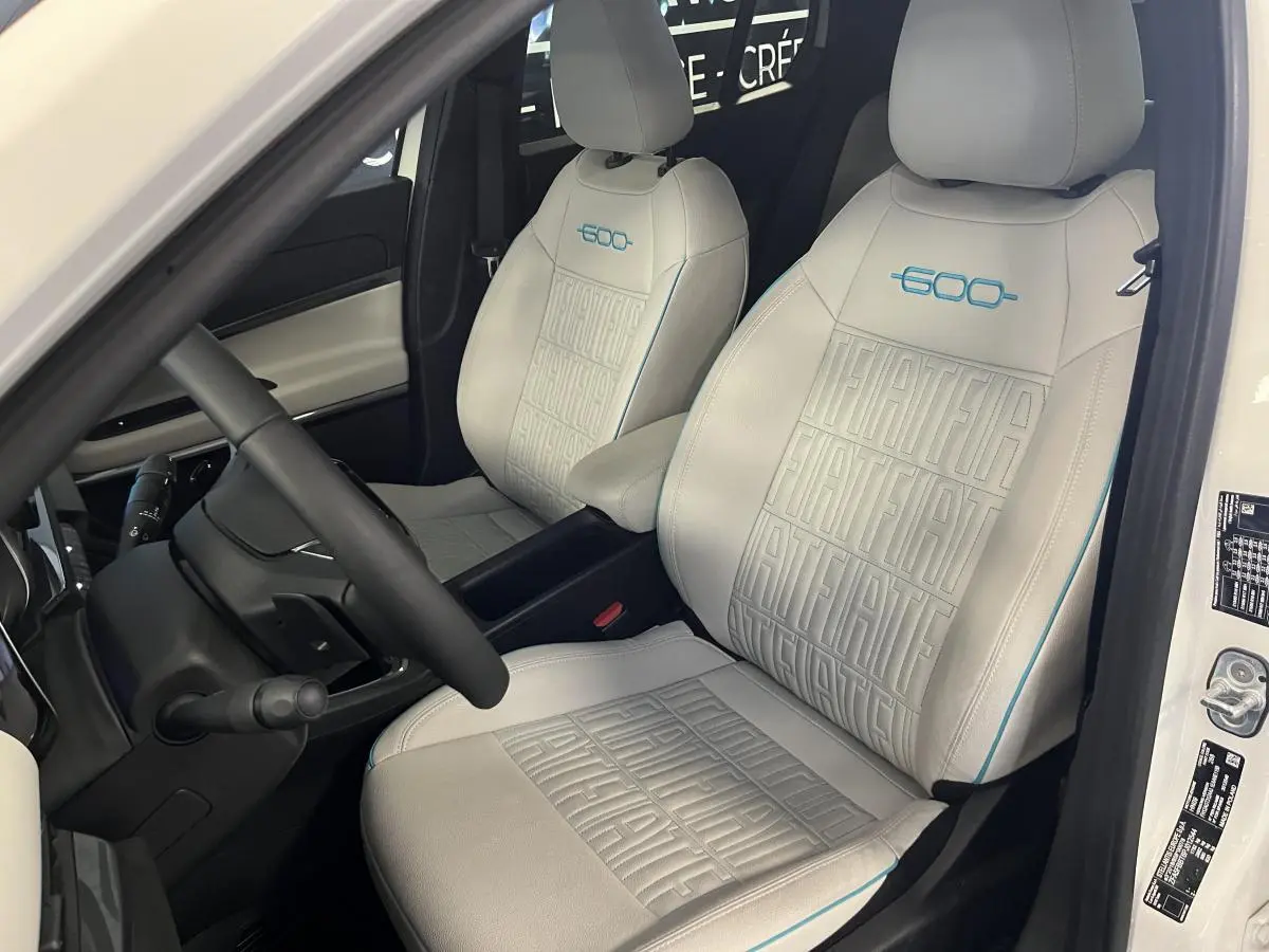 Vue intérieure côté conducteur du FIAT 600 blanc 2024, sièges ivoire avec logo 600 bleu et surpiqûres FIAT.