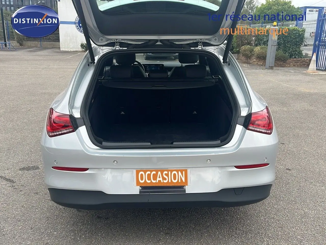 Vue arrière d'une Mercedes Classe CLA Shooting Brake 180 argent iridium avec coffre ouvert en extérieur.