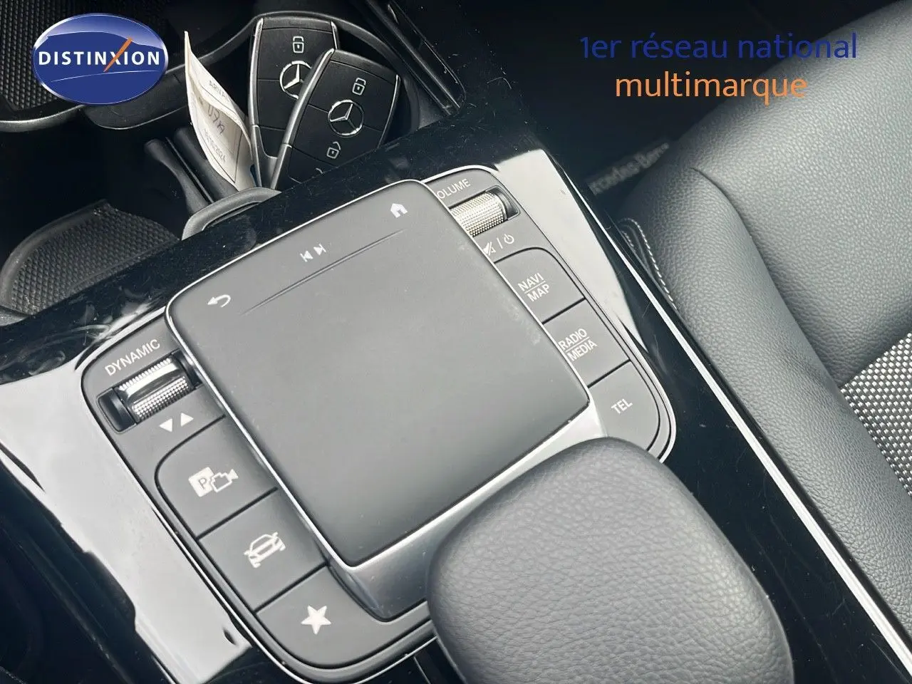 Vue rapprochée de la console centrale noire et des clés Mercedes posées sur un siège en cuir gris du CLA Shooting Brake argent.