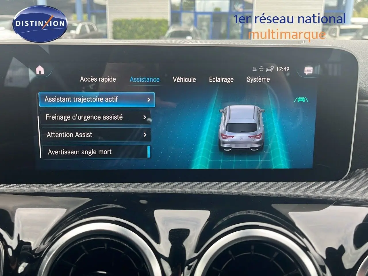 Écran central du tableau de bord d’une Mercedes CLA Shooting Brake 180 argent, affichant l’assistance à la conduite active.