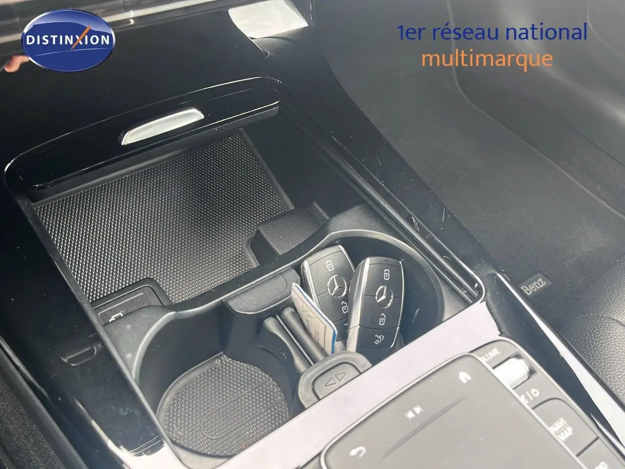 Gros plan sur la console centrale noire brillante d'une Mercedes CLA Shooting Brake argent, avec clés et porte-gobelets visibles.