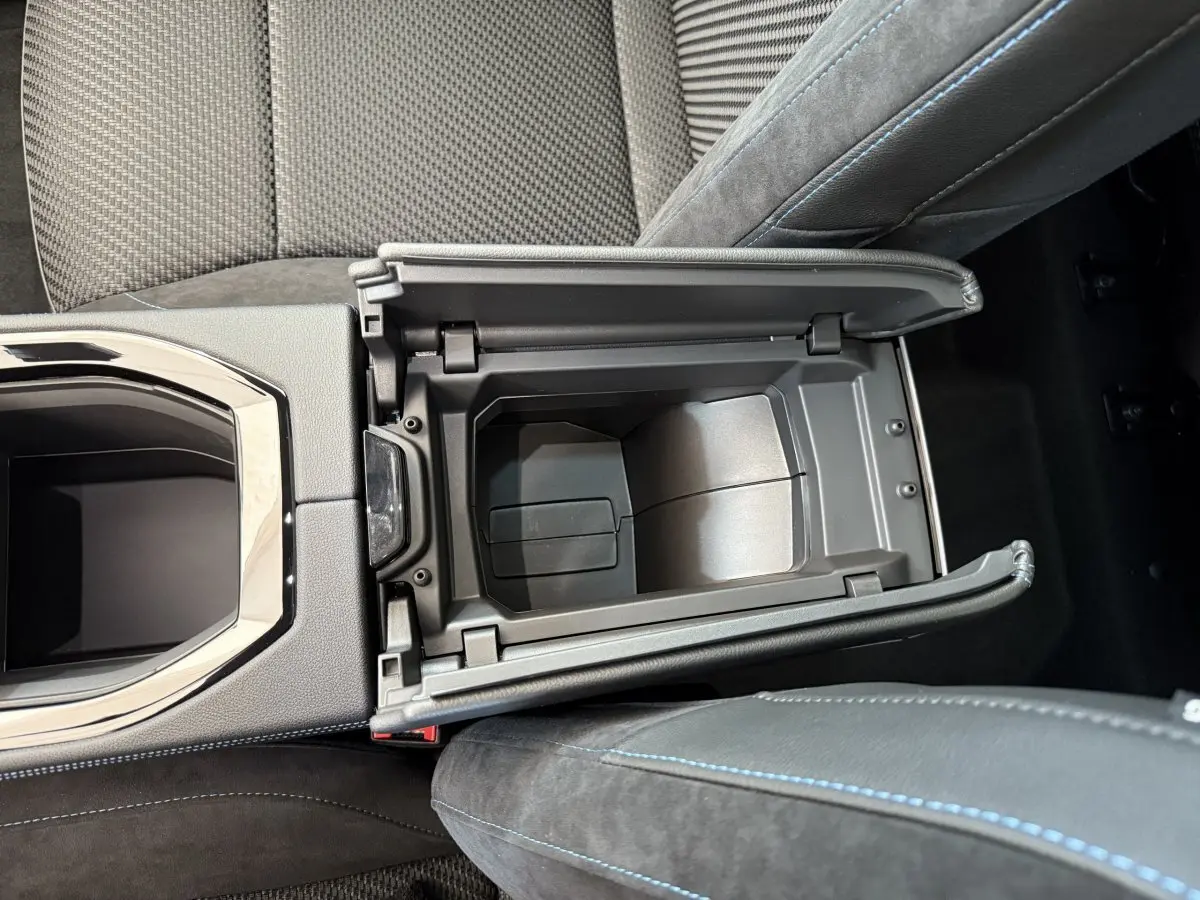 Vue plongeante sur la console centrale ouverte du Renault Espace gris foncé, soulignant les finitions cuir et surpiqûres bleues.