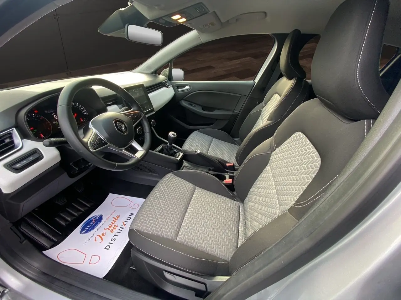 Intérieur avant de la Renault Clio V TCE 90 Evolution gris Highland avec sellerie beige et volant multifonction.