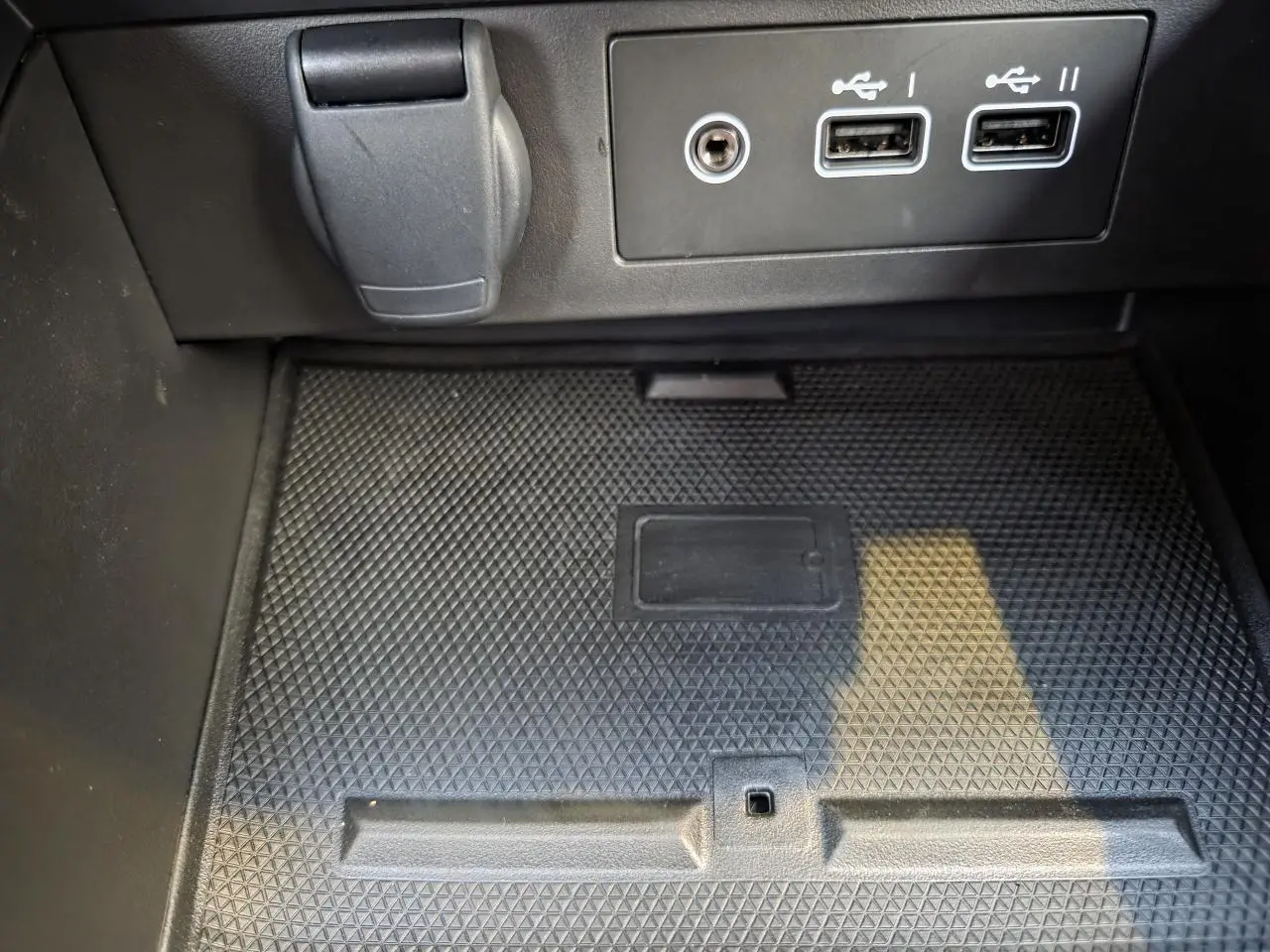 Gros plan sur la console centrale noire de la Renault Clio V hybride avec ports USB et prise 12V visibles.